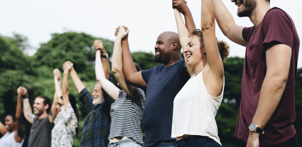 Happy diverse people holding hands in the park